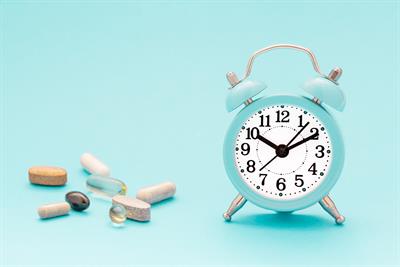Blue alarm clock with vitamin tablets next to it