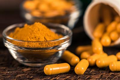 Powdered turmeric surrounded by turmeric capsules
